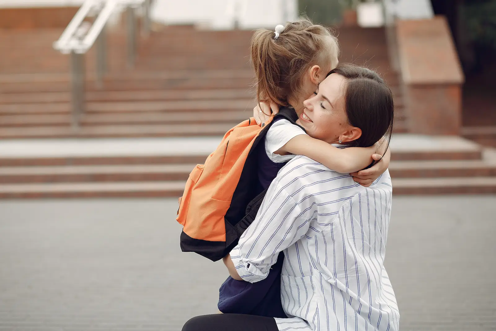 Mère et enfant devant un établissement scolaire illustrant la coéducation entre familles et professionnels