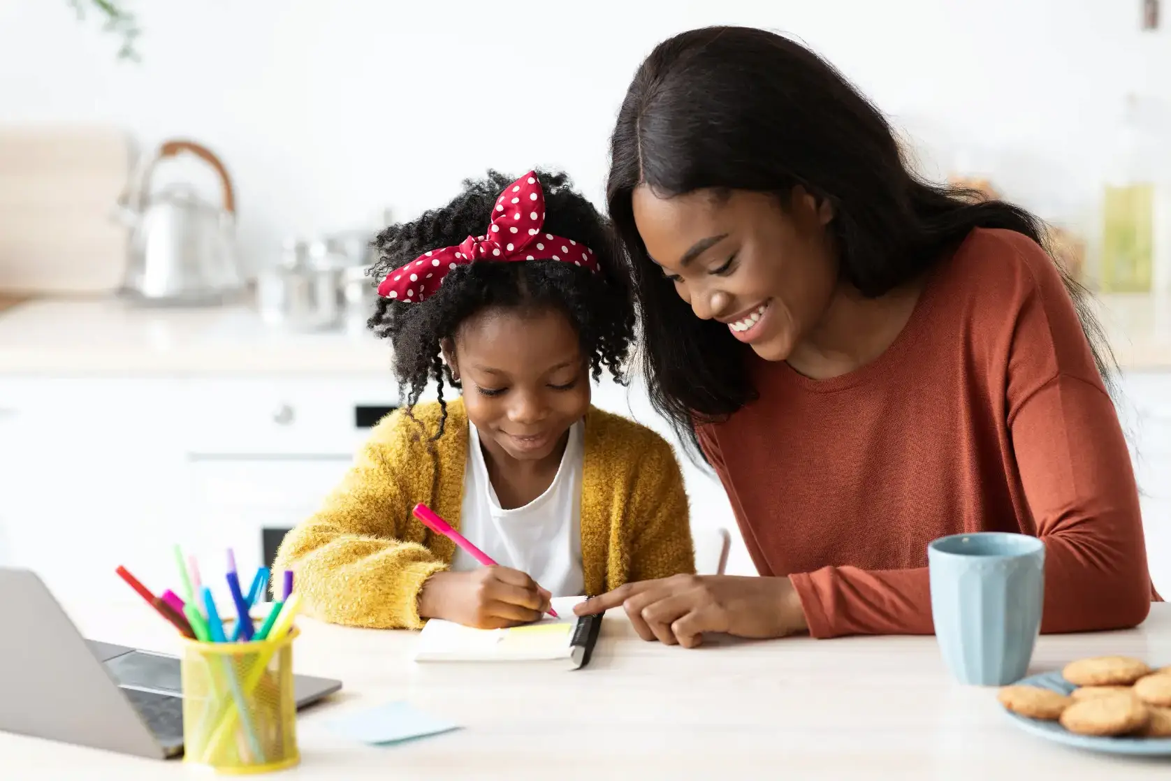 Mère accompagnant sa fille dans ses devoirs à la maison dans le cadre d’un accompagnement parental à la scolarité